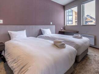 This cozy bedroom features two twin beds with plush white bedding, perfect for a relaxing stay.