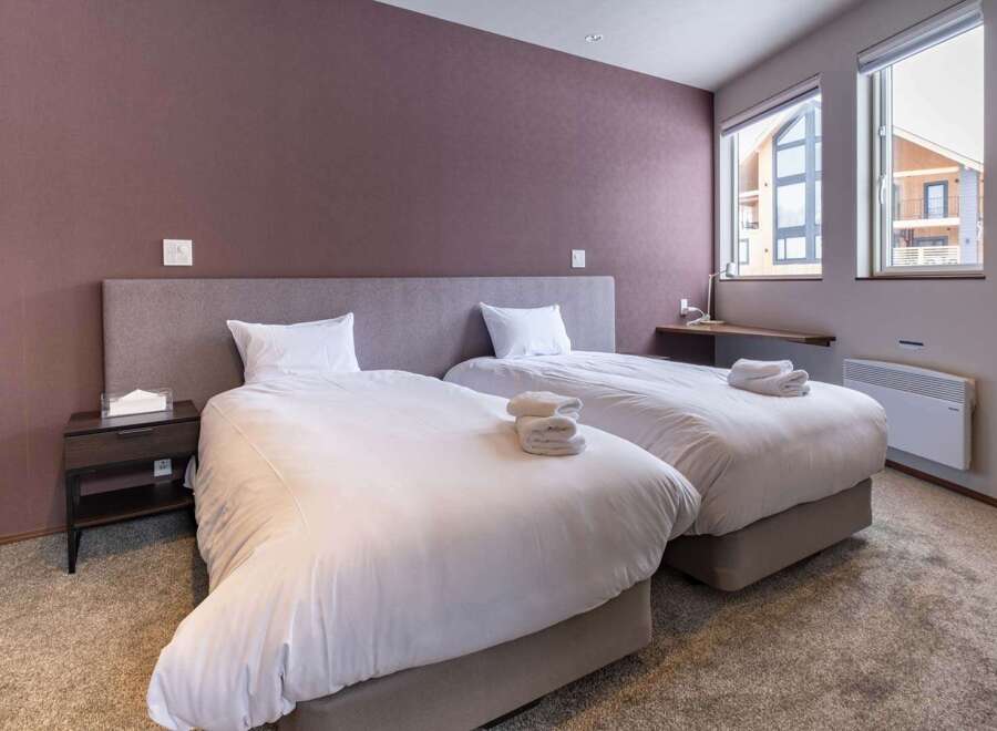 This cozy bedroom features two twin beds with plush white bedding, perfect for a relaxing stay.