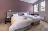 This cozy bedroom features two twin beds with plush white bedding, perfect for a relaxing stay.