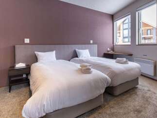 This cozy bedroom features two twin beds with plush white bedding, perfect for a relaxing stay.