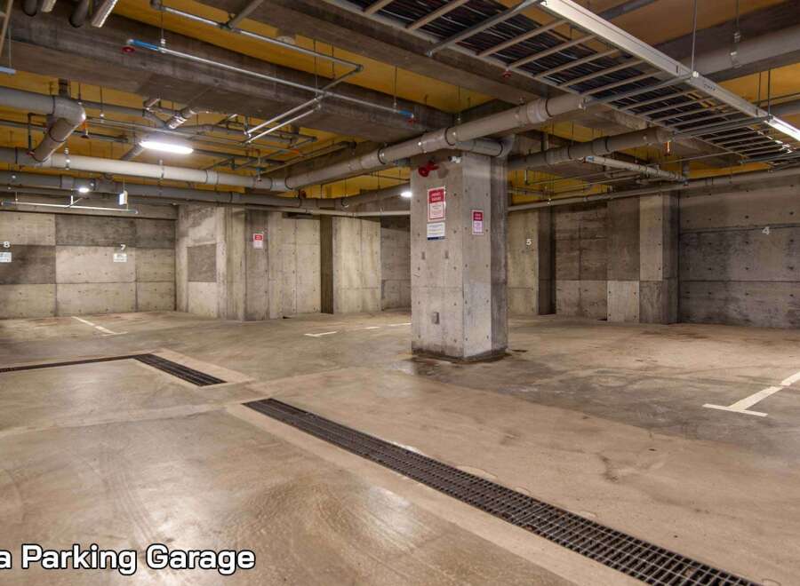 This spacious parking garage offers ample room for vehicles, featuring clearly marked parking spots and well-maintained concrete flooring.