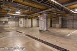 This spacious parking garage offers ample room for vehicles, featuring clearly marked parking spots and well-maintained concrete flooring.
