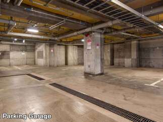 This spacious parking garage offers ample room for vehicles, featuring clearly marked parking spots and well-maintained concrete flooring.