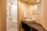 This modern bathroom boasts a sleek, built-in shower with ample shelving for toiletries and a stylish vanity with a contemporary sink.