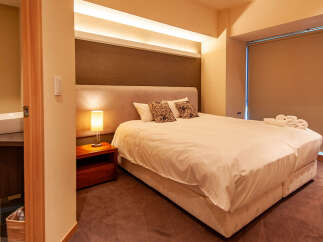 This cozy bedroom features a comfortable double bed with crisp white linens, complemented by a stylish headboard and soft pillows.