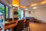 This modern apartment boasts an open-plan living area with hardwood floors, large windows offering scenic views, and a dining table with leather chairs.