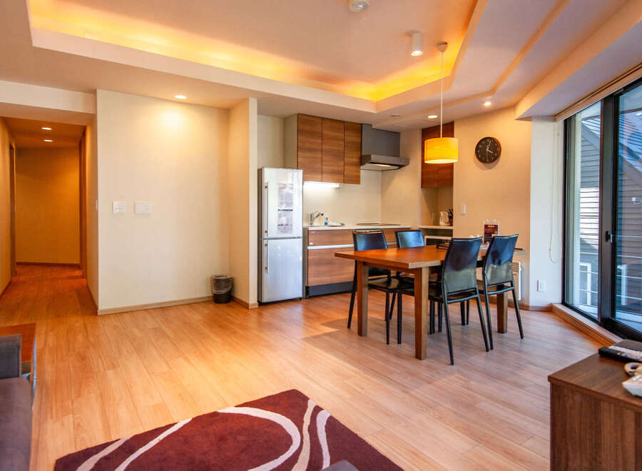 This modern apartment boasts an open-plan living area with hardwood floors, a fully equipped kitchen, and a dining table for four.