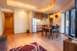 This modern apartment boasts an open-plan living area with hardwood floors, a fully equipped kitchen, and a dining table for four.