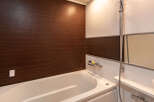 This modern bathroom boasts a sleek, built-in bathtub with a clean white finish and dark wood paneling for a sophisticated look.