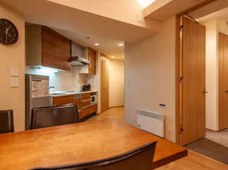 This modern apartment boasts a sleek, integrated kitchen with wood cabinetry and stainless steel appliances, perfect for preparing meals.