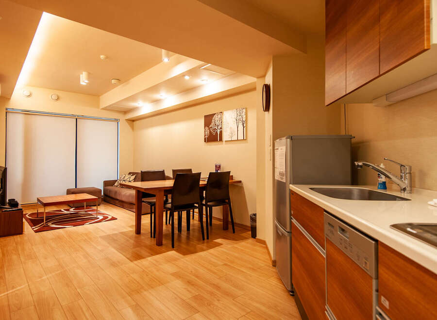 This modern apartment boasts an open-plan living area with hardwood floors, a comfortable sofa, and a dining table for four.