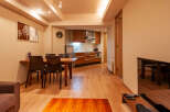 This modern apartment boasts an open-plan living area with a dining table and chairs, seamlessly flowing into a well-equipped kitchen.