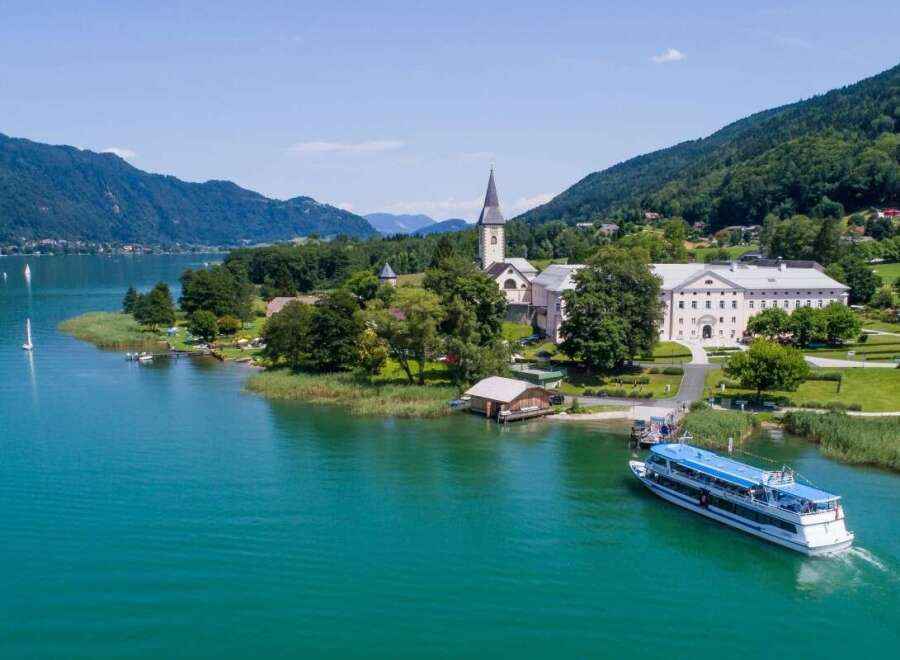 Discover the stunning beauty of this lakeside property, featuring a charming church and a grand building.