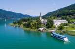 Discover the stunning beauty of this lakeside property, featuring a charming church and a grand building.