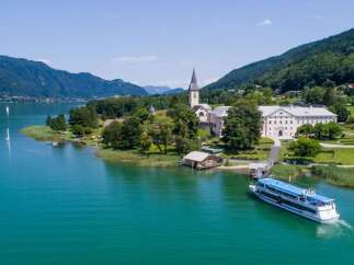 Discover the stunning beauty of this lakeside property, featuring a charming church and a grand building.