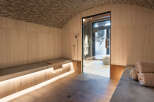 Luxurious spa with a wooden interior, featuring a built-in bench with soft lighting, a glass-enclosed shower, and plush towels.