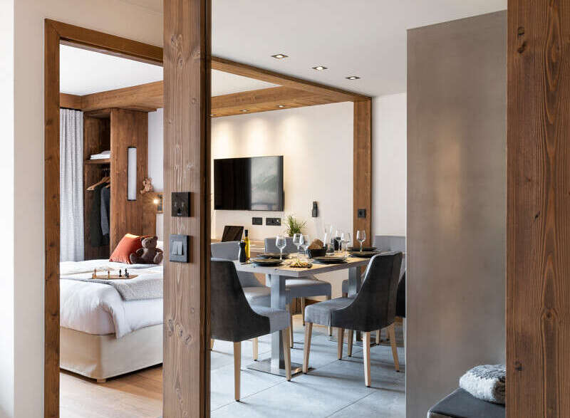 This stunning apartment boasts a spacious open-plan living area with a modern dining set and a large mirror reflecting the stylish interior.