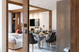This stunning apartment boasts a spacious open-plan living area with a modern dining set and a large mirror reflecting the stylish interior.