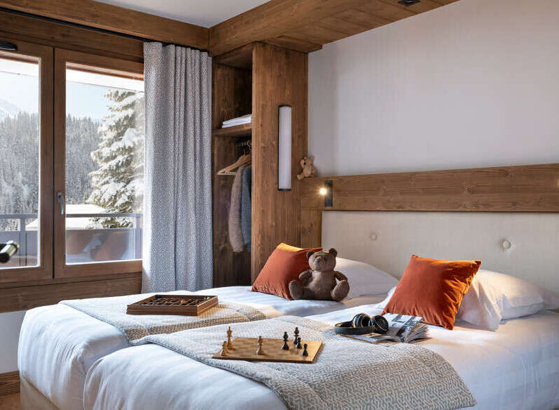 Cozy twin bedroom with mountain views, featuring a wooden headboard, plush bedding, and a built-in wardrobe.