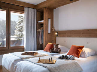 Cozy twin bedroom with mountain views, featuring a wooden headboard, plush bedding, and a built-in wardrobe.