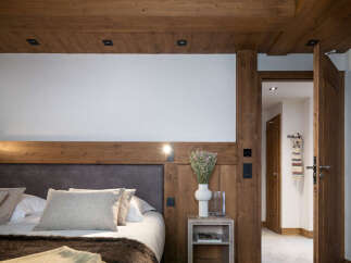 This luxurious bedroom boasts a cozy, rustic-chic design with exposed wooden beams and a plush bed dressed in soft linens.