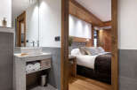 This stunning hotel room boasts a modern bathroom with a granite vanity and a spacious bedroom with a cozy bed and wooden accents.