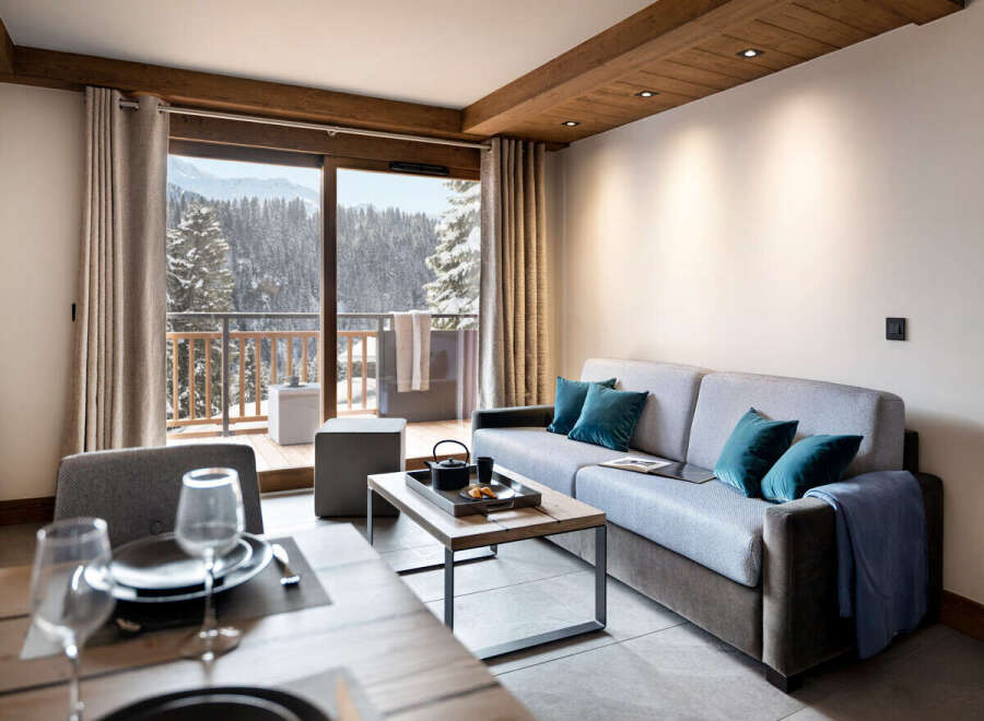 This stunning apartment boasts breathtaking views of snow-capped mountains, accessible through large sliding doors leading to a private balcony.