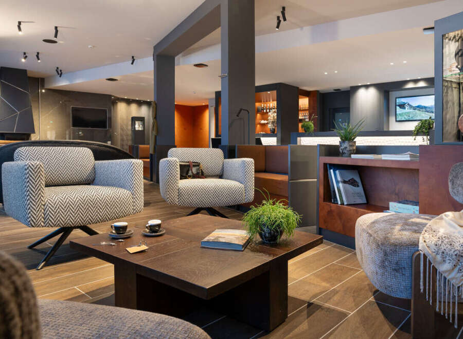 Relax in style in our luxurious hotel lobby, featuring comfortable armchairs, a coffee table with books, and a modern fireplace.