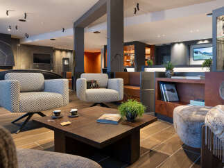Relax in style in our luxurious hotel lobby, featuring comfortable armchairs, a coffee table with books, and a modern fireplace.