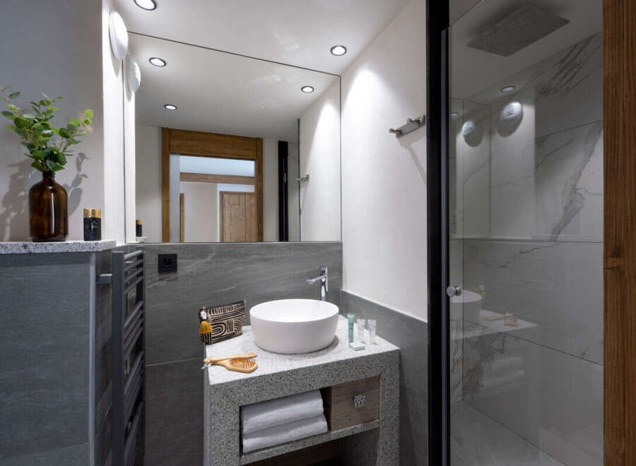 This modern bathroom boasts a sleek granite vanity with a white vessel sink, complemented by stylish accessories and ample storage.