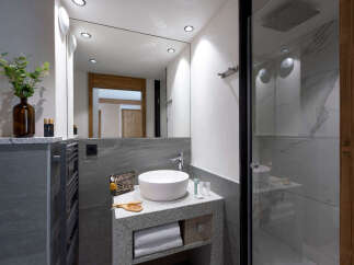 This modern bathroom boasts a sleek granite vanity with a white vessel sink, complemented by stylish accessories and ample storage.