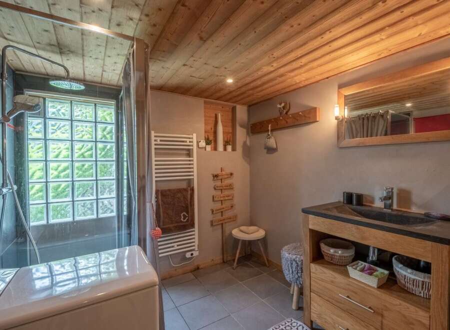 Cozy chalet bathroom with wooden features, including a glass block window, heated towel rack, and stylish vanity with storage.