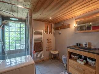 Cozy chalet bathroom with wooden features, including a glass block window, heated towel rack, and stylish vanity with storage.