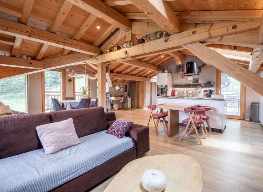 This stunning chalet boasts a spacious open-plan living area with exposed wooden beams, creating a warm and inviting atmosphere.