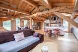 This stunning chalet boasts a spacious open-plan living area with exposed wooden beams, creating a warm and inviting atmosphere.
