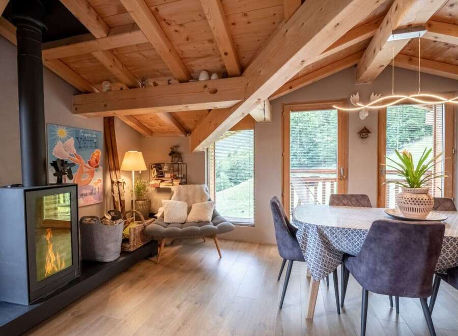 Cozy chalet with exposed wooden beams, a modern wood-burning stove, and a spacious dining area.