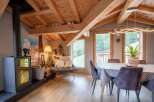 Cozy chalet with exposed wooden beams, a modern wood-burning stove, and a spacious dining area.