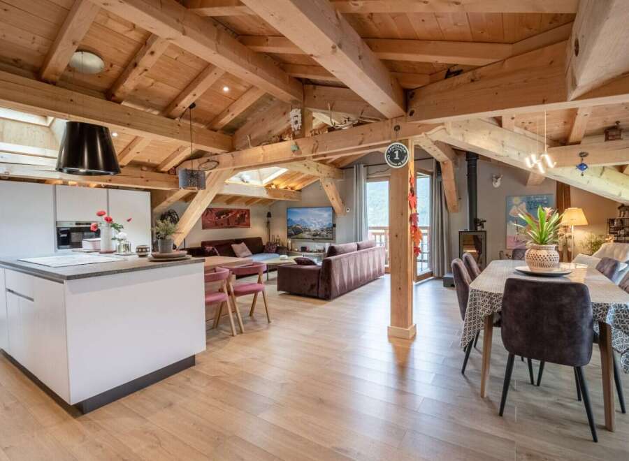 This stunning chalet boasts a spacious open-plan living area with exposed wooden beams, creating a warm and inviting atmosphere.