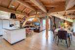 This stunning chalet boasts a spacious open-plan living area with exposed wooden beams, creating a warm and inviting atmosphere.