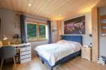 Cozy bedroom with wooden ceiling and large window offering scenic views.
