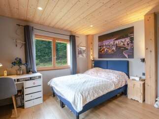 Cozy bedroom with wooden ceiling and large window offering scenic views.