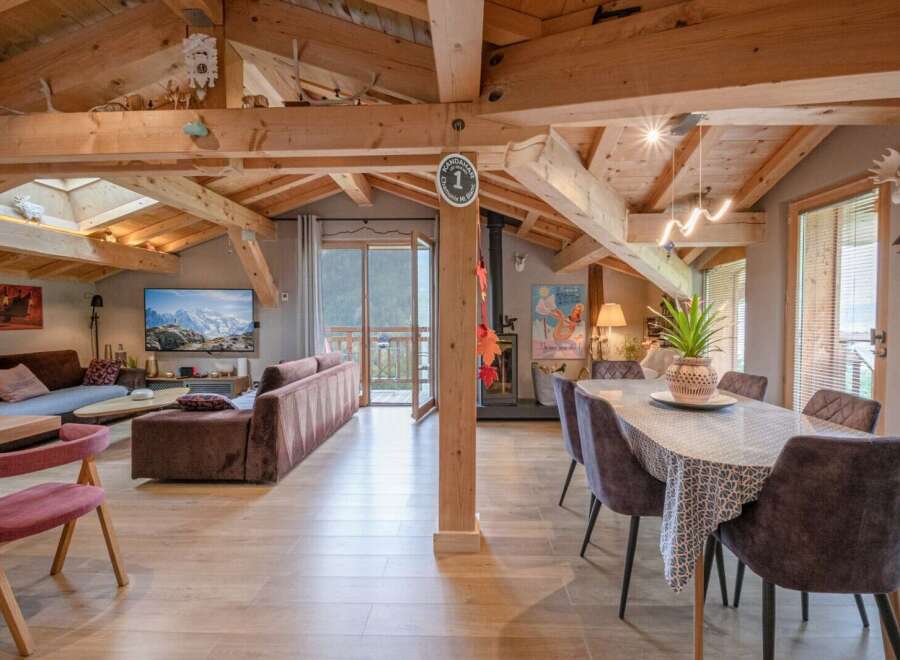This stunning chalet boasts a spacious open-plan living area with exposed wooden beams, creating a warm and inviting atmosphere.