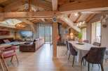 This stunning chalet boasts a spacious open-plan living area with exposed wooden beams, creating a warm and inviting atmosphere.