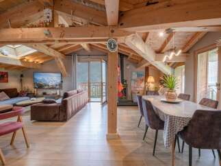 This stunning chalet boasts a spacious open-plan living area with exposed wooden beams, creating a warm and inviting atmosphere.