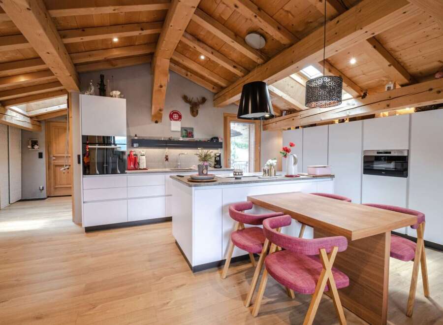 This stunning chalet boasts a spacious, open-plan kitchen with modern white cabinetry and high-end appliances.