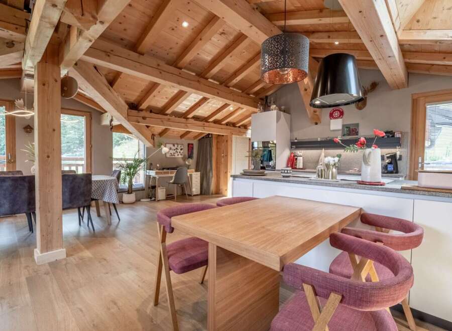 This stunning chalet boasts a spacious open-plan living area with exposed wooden beams and large windows offering breathtaking views.