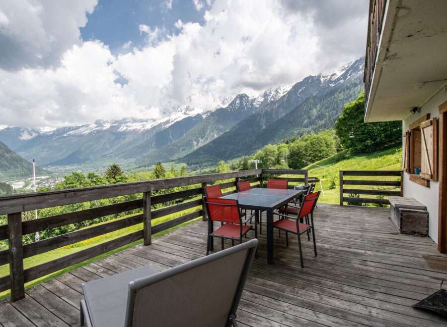 Mountain view deck with wooden dining set and lounge chairs.