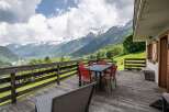 Mountain view deck with wooden dining set and lounge chairs.