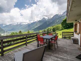 Mountain view deck with wooden dining set and lounge chairs.