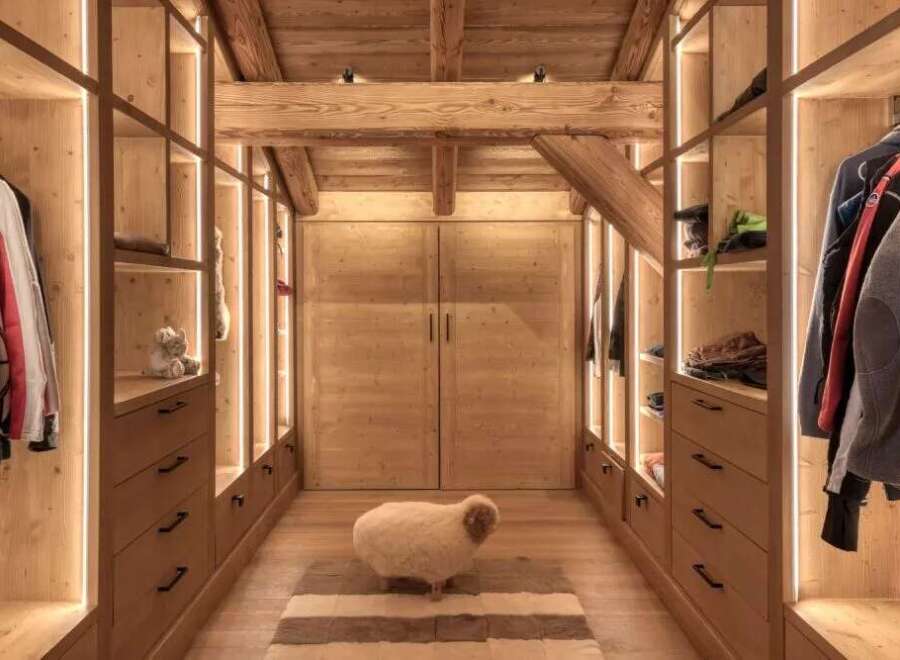 Step into luxury with this stunning walk-in closet, showcasing exquisite wooden craftsmanship and ambient lighting.